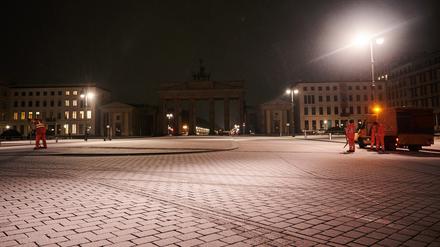 Mitarbeiter der Stadtreinigung BSR arbeiten am Montagmorgen bei Schnee vor dem Brandenburger Tor.