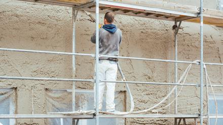 Worker plastering outer wall of newly built house