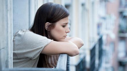 young sad beautiful woman suffering depression looking worried and wasted on home balcony with an urban view in lonely depressed and desperate female concept