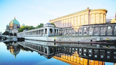 Die Alte Nationalgalerie (r.) und der Berliner Dom (l.) spiegeln sich im Licht der aufgehenden Sonne in der Spree.