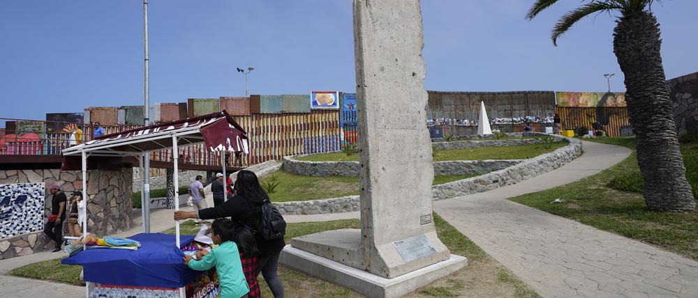 Eine Familie schiebt einen Imbisswagen an einem Stück der Berliner Mauer vorbei, die in der Nähe der Grenzmauer, die die Vereinigten Staaten von Mexiko trennt, ausgestellt ist.