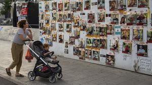 Eine Passantin betrachtet die Fotos der im Gazastreifen festgehaltenen Geiseln, die an den Wänden des Geiselplatzes in Tel Aviv angebracht sind.