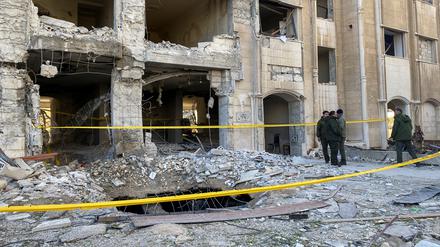 Polizisten stehen in der Nähe eines beschädigten Gebäudes am Ort eines Raketenangriffs im Kafr Sousa-Viertel im Zentrum von Damaskus.