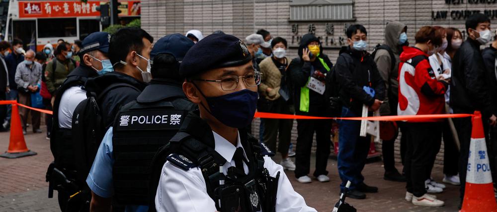 Polizisten stehen während der Anhörung der 47 pro-demokratischen Aktivisten, die der Verschwörung zum Umsturz nach dem Gesetz über die nationale Sicherheit angeklagt sind, vor dem Gebäude des West Kowloon Magistrates’ Courts in Hongkong.