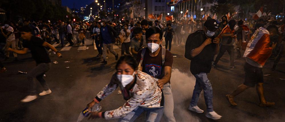 Anhänger des ehemaligen Präsidenten Pedro Castillo schützen sich vor Tränengas.