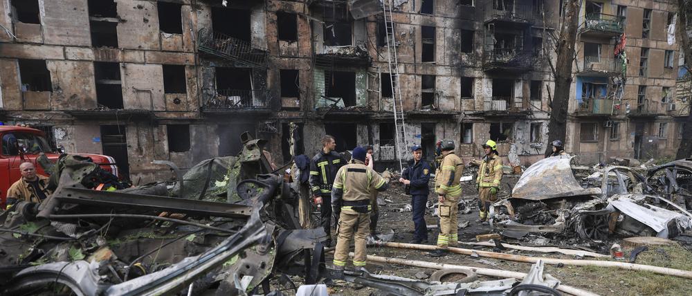 Rettungskräfte inspizieren ein durch Raketenangriff beschädigtes, mehrstöckiges Wohnhaus.