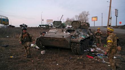 Ukrainische Soldaten stehen neben einem zerstörten gepanzerten Fahrzeug, das angeblich der russischen Armee gehört, außerhalb von Charkiw (Archivbild).