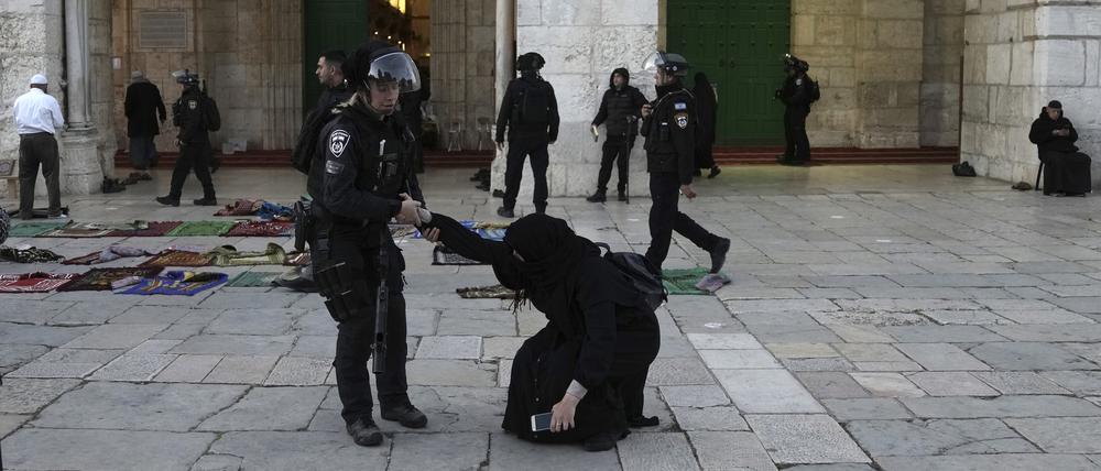 Eine israelische Polizistin zieht eine Gläubige hoch, die auf dem Gelände der Al-Aqsa-Moschee während des muslimischen heiligen Monats Ramadan in der Altstadt von Jerusalem auf dem Boden saß.
