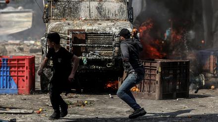 22.02.2023, Palästinensische Gebiete, Nablus: Palästinenser rennen während der Zusammenstöße im Westjordanland vor ein Fahrzeug der israelischen Armee. Foto: Ayman Nobani/dpa +++ dpa-Bildfunk +++