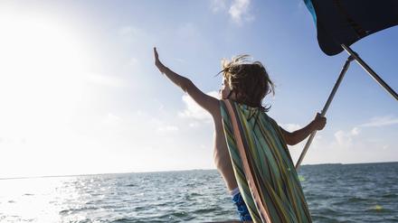 Zugewandt. Ein kleiner Junge lehnt sich aus dem Boote heraus der Sonne entgegen. Gesehen auf Grand Cayman Island. 