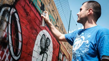 Graffiti-Künstler Ibo Omari übermalt ein Hakenkreuz-Graffiti an einer Wand in Berlin, 2016.