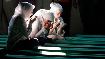 Bosnische Muslimas beten  vor Särgen von Opfern des Massakers von Srebrenica, die in einer Gedenkstätte aufgestellt wurden, 2012.