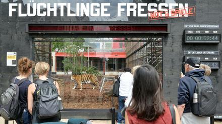 Ein Tiger ist in Berlin vor dem Maxim Gorki Theater im Tigergehege mit der Aufschrift "Flüchtlinge Fressen" zu sehen. 