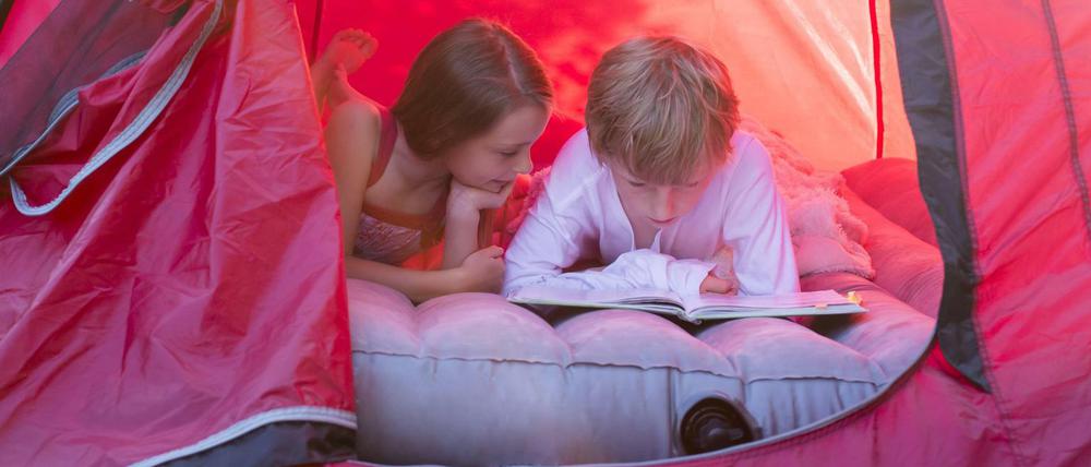 Boy and girl reading lying in a red tent with a book model released Symbolfoto PUBLICATIONxINxGERxSUIxAUTxHUNxONLY SARF001930