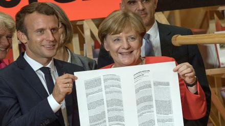 Kanzlerin Merkel und Frankreichs Präsident Macron halten auf der Buchmesse die Erklärung der Menschenrechte.