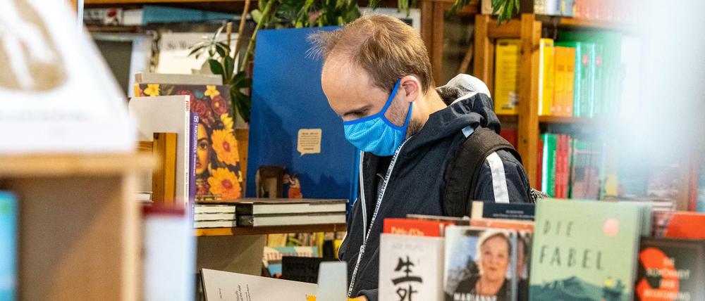 Auf der Suche nach Corona-Literatur? Ein Kunde steht mit Mundschutz in einem Buchladen in Regensburg 