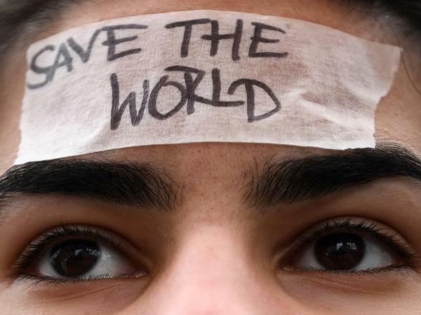 Eine Schülerin trägt während einer Demonstration von "Fridays for Future" ein Band mit der Aufschrift "Save the World" auf ihrer Stirn. 