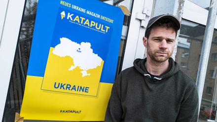 Der ehemalige Katapult-Geschäftsführer Benjamin Fredrich vor einem Poster des Ukraine-Magazins.