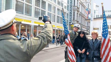 Bildabgleich. Touristinnen lassen sich am ehemaligen Grenzübergang Checkpoint Charlie mit Soldaten-Darstellern fotografieren.