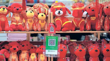 Im Jahr des Hundes. Ladenregal mit vierbeinigen Maskottchen. Die Schilder mit den QR-Codes gehören zu den allgegenwärtigen Bezahlverfahren Alipay (oben) und WeChat, dem chinesischen Pendant von WhatsApp. 
