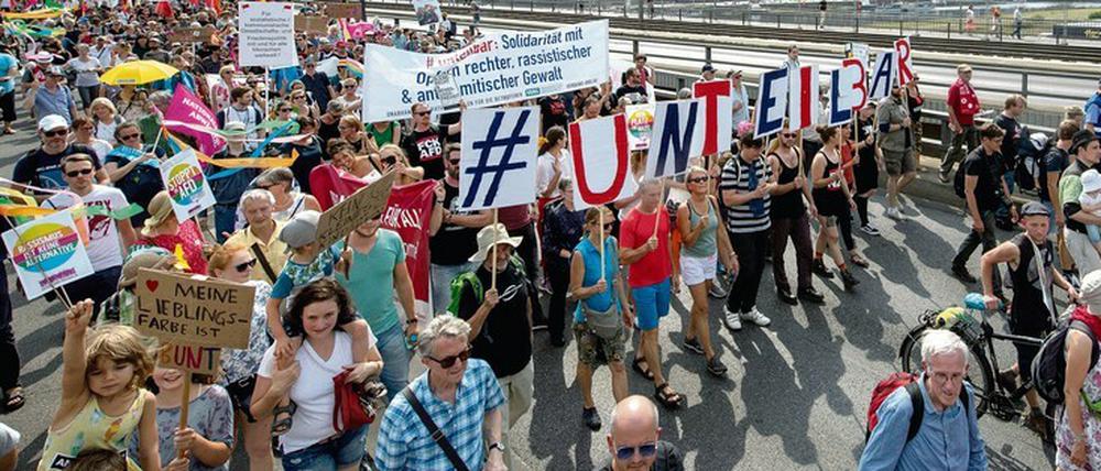 Anhänger des Bündnisses #unteilbar gehen August 2019 über die Carolabrücke vor der historischen Altstadtkulisse.