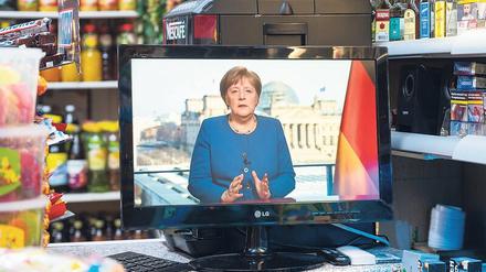 In einem Berliner Spätkauf läuft die TV-Ansprache von Angela Merkel auf einem kleinen Fernseher.