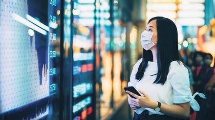 Besorgter Blick. Eine Businessfrau checkt in Hongkong die Aktienkurse auf einem Monitor.