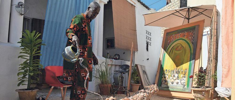 Bewässerung eines Kunstwerks. El Hadji Sy begießt im Hof seines Atelierhauses ein aus Muscheln gebildetes Krokodil, das im Juni auf der Dakar-Biennale zu sehen sein wird.