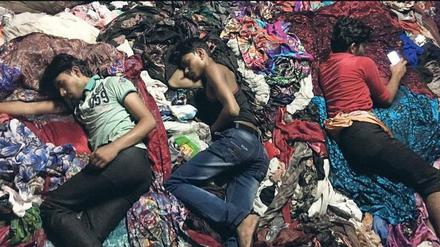 Erschöpft. Indische Arbeiter schlafen im Stofflager.