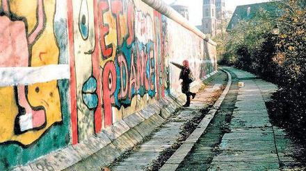 Antifaschistischer Schutzwall, Ghettomarkierung, Bildfläche. Die Mauer in den achtziger Jahren von der Kreuzberger Seite - und eine Aktionskünstlerin bei der Arbeit. Foto: Salzgeber