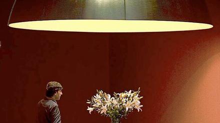 Ein Besucher nähert sich an eine Lampe von Ingo Maurer auf einer Ausstellung 2005. Maurer wird auch als "Poet des Lichts" bezeichnet.