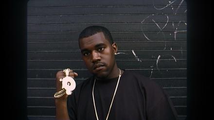 Ein junger Kanye West zeigt seinen Schmuck.