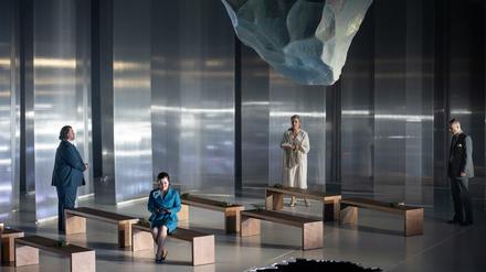 Ein tauender Eisblock hängt im frostigen Bühnenbild von Paolo Fantin bedrohlich über den Köpfen der Darsteller*innen.