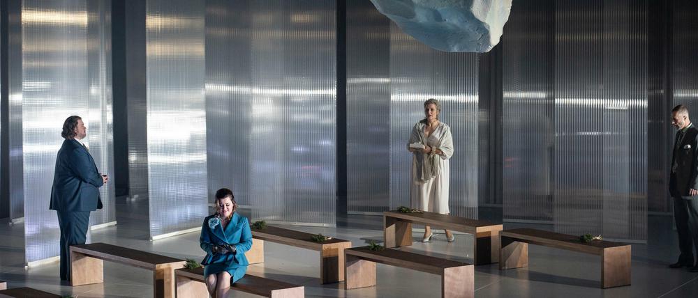 Ein tauender Eisblock hängt im frostigen Bühnenbild von Paolo Fantin bedrohlich über den Köpfen der Darsteller*innen.