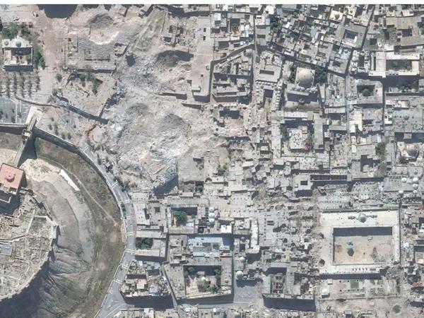 Aleppo 2010 (oben) und 2014. Der Wiederaufbau der historischen Altstadt ist für Syrien von großer Bedeutung. Links ist die Zitadelle zu sehen, das Viereck rechts ist die Umayyadenmoschee mit dem zerstörten Minarett.