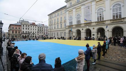 Einwohner von Lwiw enthüllen vor dem Rathaus am Rynok Platz die ukrainische Flagge. Anlass war im März 2021 der Jahrestag der Nationalhymne des Landes.