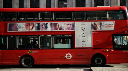 Ein traditioneller roter Doppeldeckerbus mit Werbung für die Netflix-Serie "The Crown" fährt durch das Zentrum von London. 