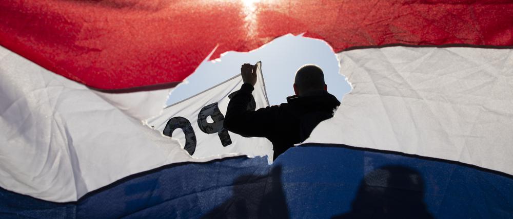 Riss in der Flagge. Teilnehmer einer Demonstration gegen die Corona-Maßnahmen in Amsterdam.