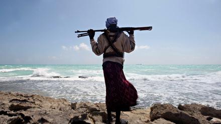 Ein somalischer Pirat an der Nordostküste des Landes, am Horizont ein Frachter. Das Bild stammt aus dem Jahr 2010. 