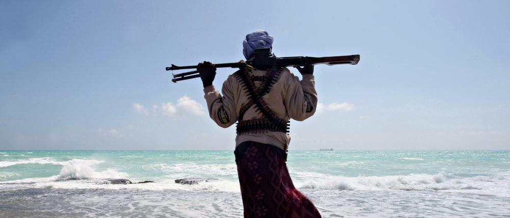 Ein somalischer Pirat an der Nordostküste des Landes, am Horizont ein Frachter. Das Bild stammt aus dem Jahr 2010. 