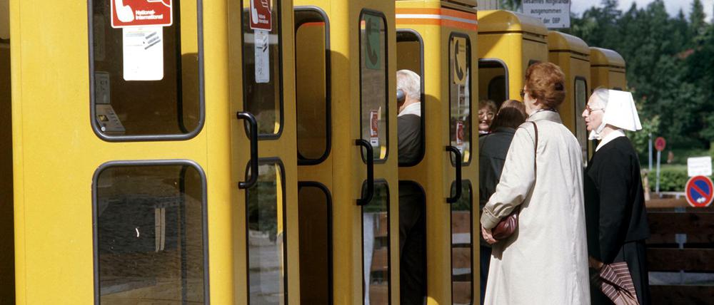 Als es noch keine Smartphones gab. Personen warten vor einer gelben Telefonzelle, 1985.