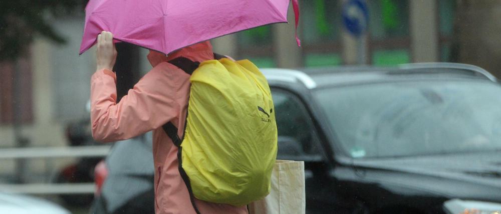 Wasseralarm. Eine Frau läuft am 30.Juni 2017 mit einem Regenschirm durch Berlin. 
