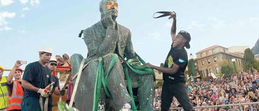 Entkolonialisierung. Studenten attackieren die Statue des britischen Politikers und Bergbaumagnaten Cecil Rhodes auf dem Gelände der Universität von Kapstadt. Nach monatelangen Protesten wurde das Standbild am 9. April 2015 entfernt.