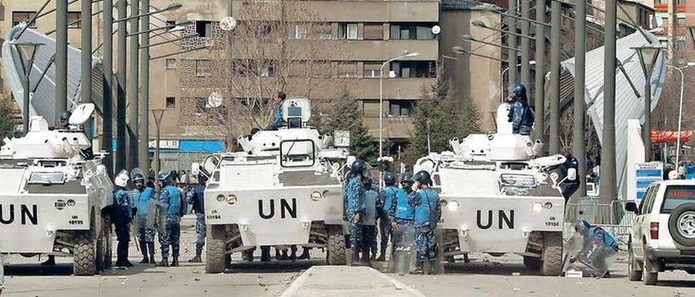 Eine UN-Polizeitruppe hält im März 2004 Kosovo-Albaner und Kosovo-Serben in der ethnisch geteilten Stadt Kosovska Mitrovica auf Distanz. 