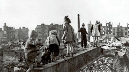 Eine Gruppe Kinder spielt in den Trümmern einer zerstörten Stadt im Deutschland der Nachkriegszeit. 