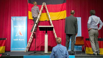 Helfer hängen vor der 1. Deutschlandtagung der Alternativen Mitte der AfD in Tettau (Bayern) eine Deutschlandfahne auf.