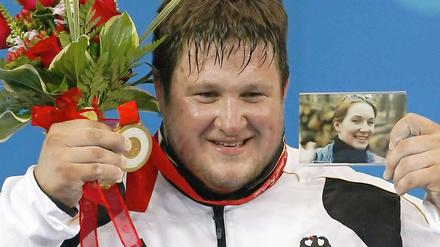 Die Menschen lieben am Sport die großen Gefühle: Der deutsche Gewichtheber Matthias Steiner zeigt nach seinem Olympiasieg 2008 in Peking neben der Goldmedaille und roten Rosen auch ein Foto seiner bei einem Unfall gestorbenen Frau.