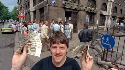 Nach langem Schlangestehen vor einer Leipziger Bank freut sich dieser junge Mann über seine D-Mark-Banknoten am 1. Juli 1990