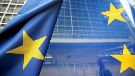 Und sie leuchten doch: Europas Sterne auf einer Flagge, im Hintergrund die Europäische Kommission in Brüssel.