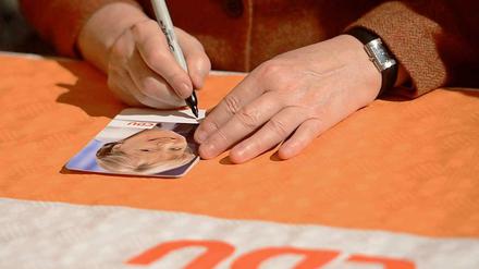 Was ist die Handschrift der CDU? Angela Merkel unterschreibt Autogrammkarten.
